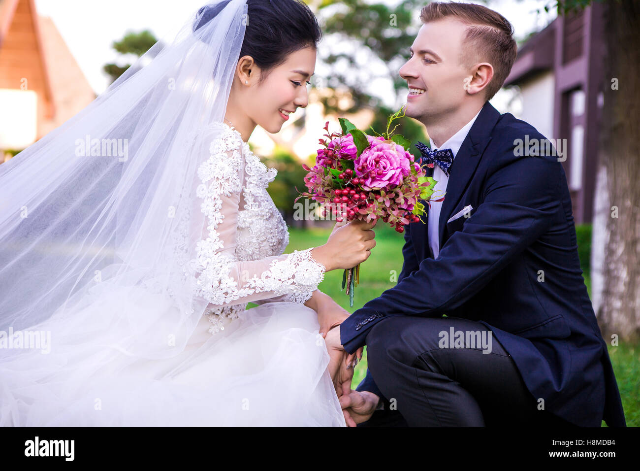 Glückliche Bräutigam Blick auf schöne Braut hält Blumenstrauss im freien Stockfoto