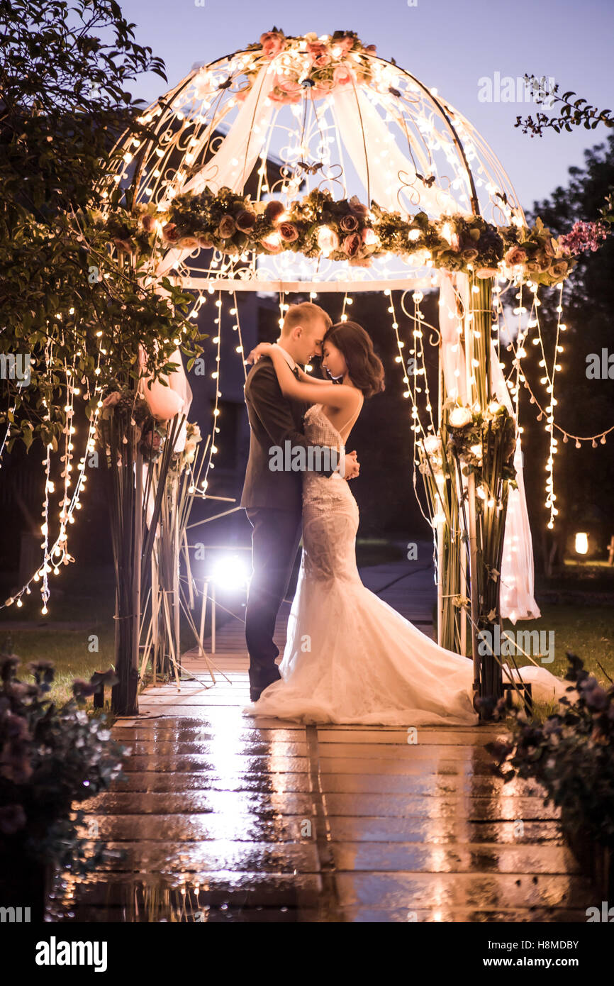 Seitenansicht der elegante Paar umfassend in Pavillon nachts beleuchtet Stockfoto