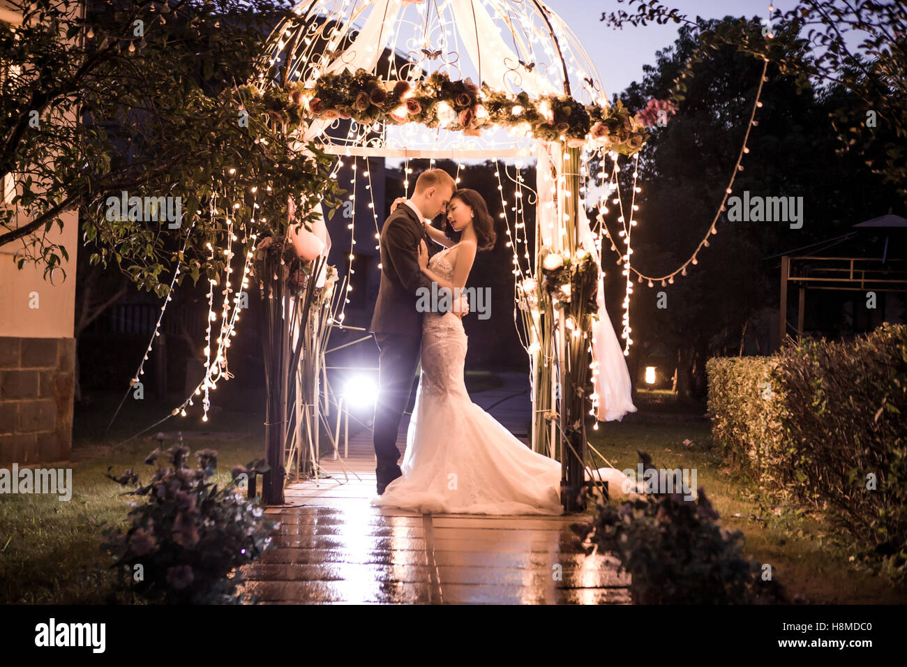 Elegante Paar umarmt im Pavillon nachts beleuchtet Stockfoto