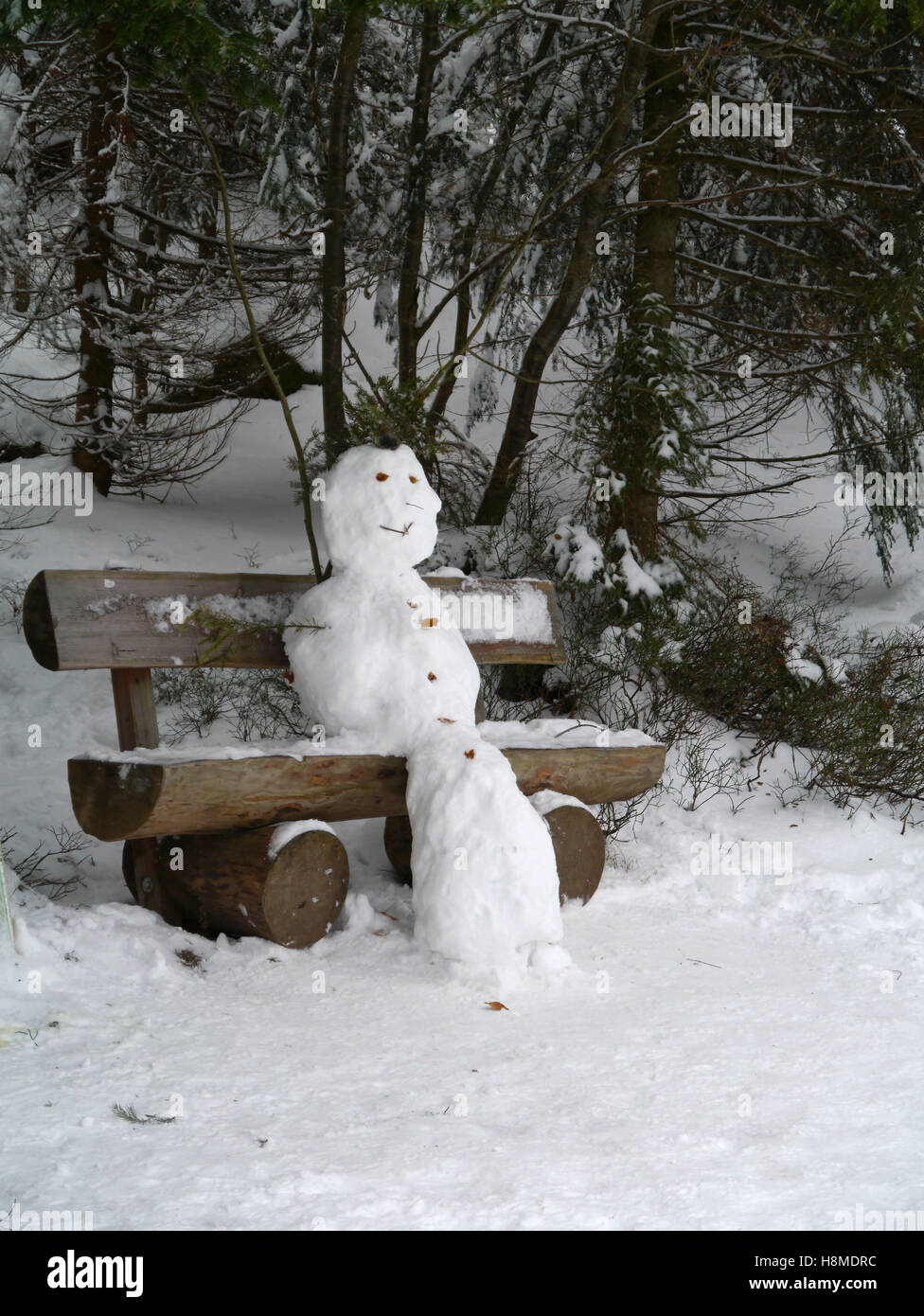 Schneemann sitzen auf einer Holzbank Stockfoto