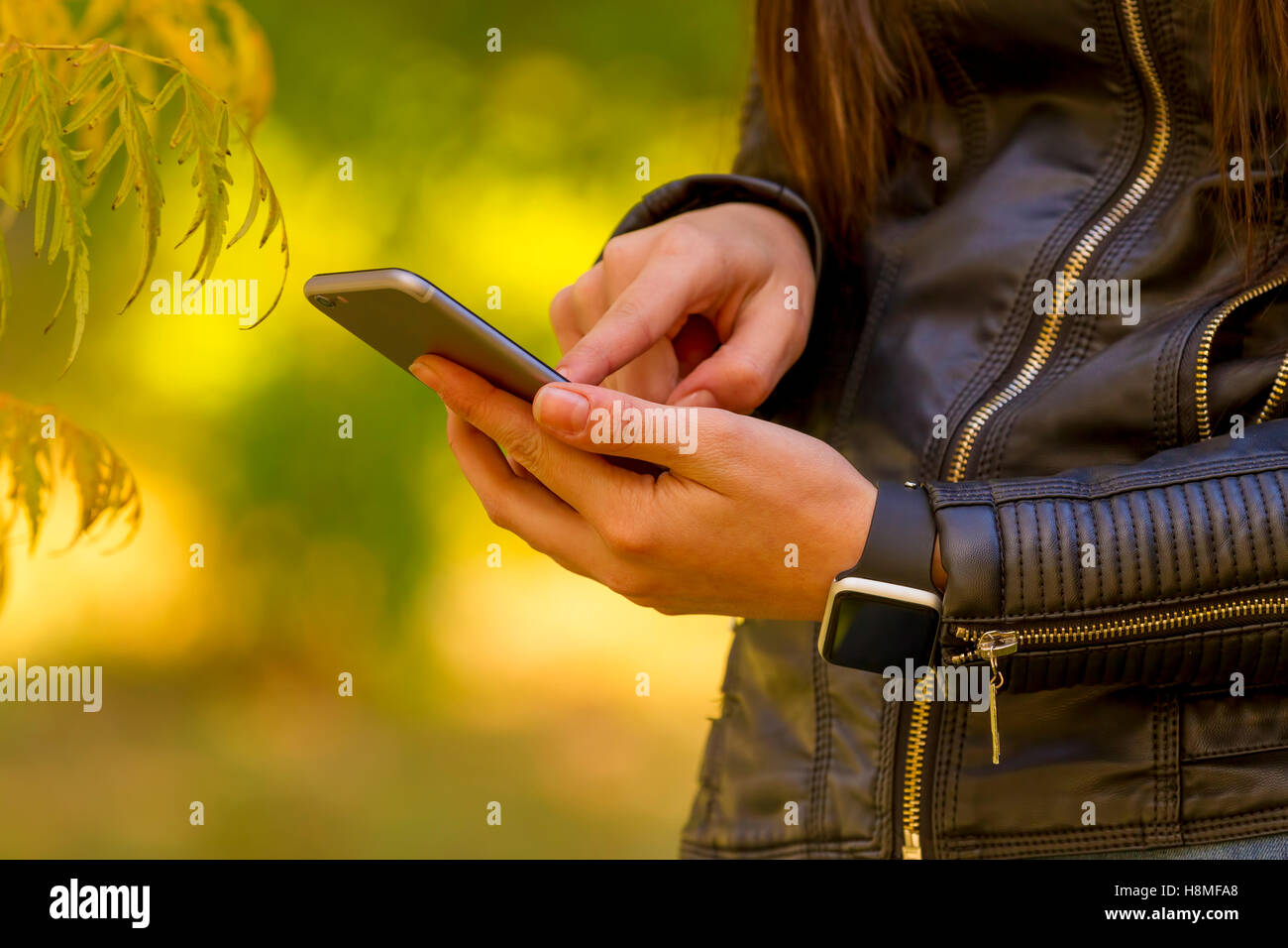 Junges Mädchen mit Smartphone im Park, trägt Smartwatch in alltäglichen Lebensstil. Konzentrieren Sie sich auf smart Phone! Stockfoto