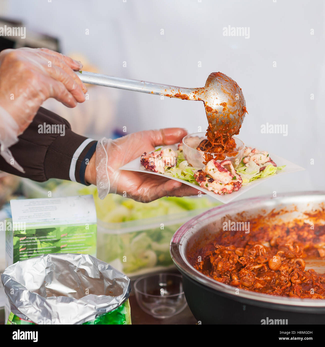Streetfood. Die Hände des Küchenchefs bereiten Sie ein Gericht aus gedünsteten Tintenfisch. Stockfoto