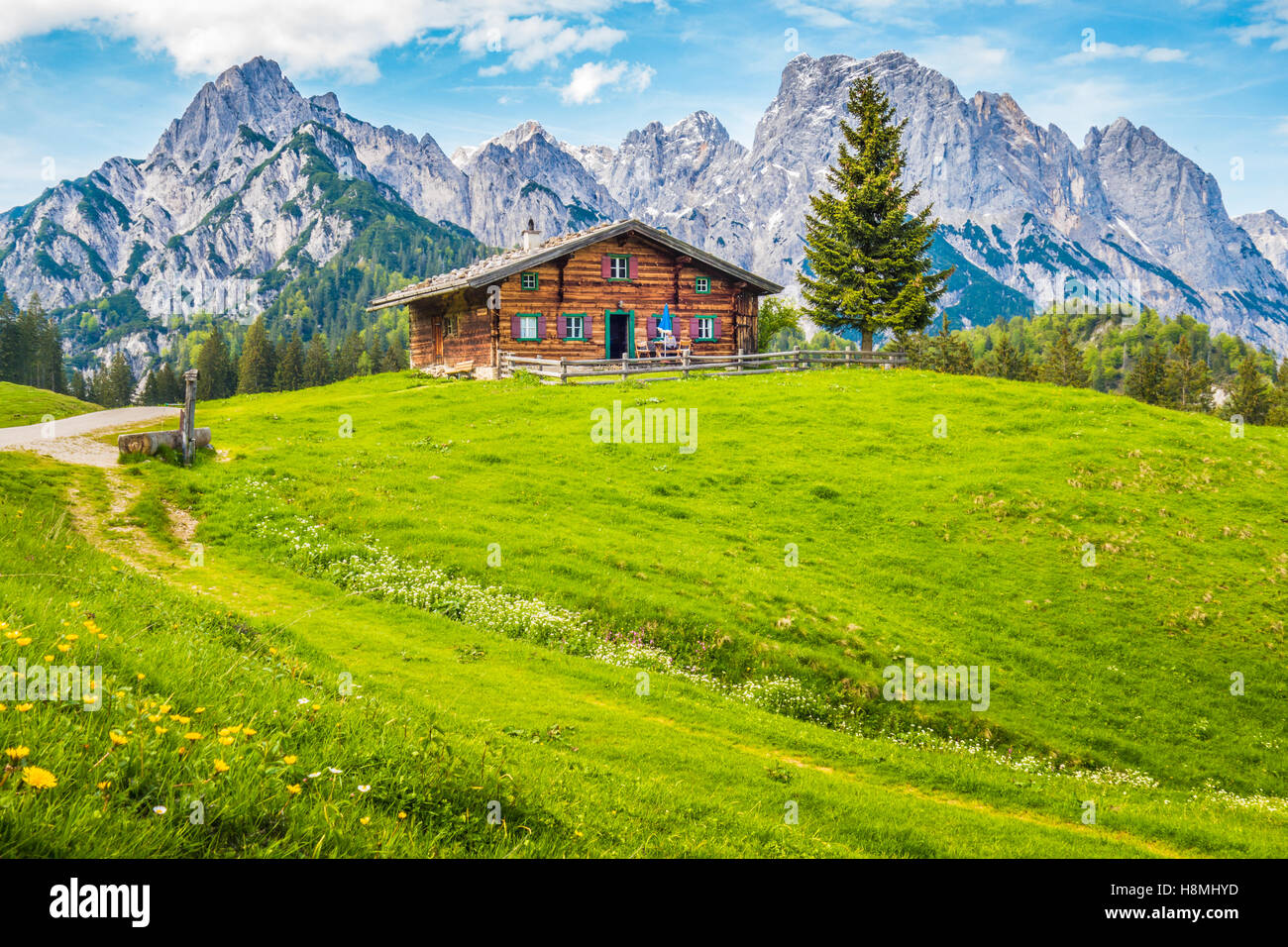 Panoramablick auf der idyllischen Bergwelt der Alpen mit traditionellen Berghütte und frische grüne Almen an einem sonnigen Tag im Sommer Stockfoto