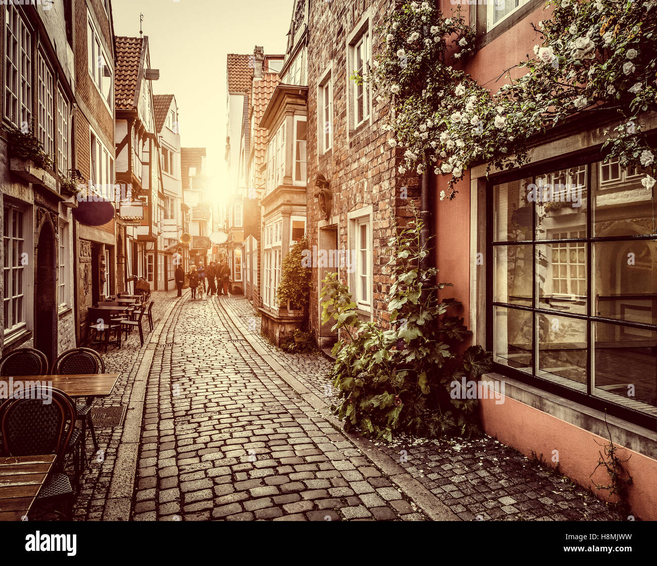 Bezaubernde Straßenszene in eine alte Stadt in Europa bei Sonnenuntergang mit Pastell getönt Retro-Vintage-Filter und Objektiv-Flare-Sonnenlicht-Effekt Stockfoto