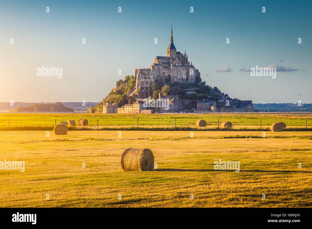 Klassische Ansicht des berühmten historischen Le Mont Saint-Michel im schönen Abendlicht bei Sonnenuntergang im Sommer mit Heuballen auf Feldern mit, Normandie, Frankreich Stockfoto