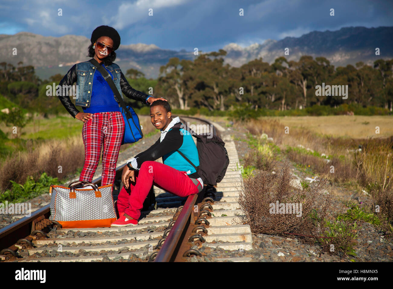 afrikanischer Mann und ein Mädchen warten auf Zug auf den Gleisen Stockfoto