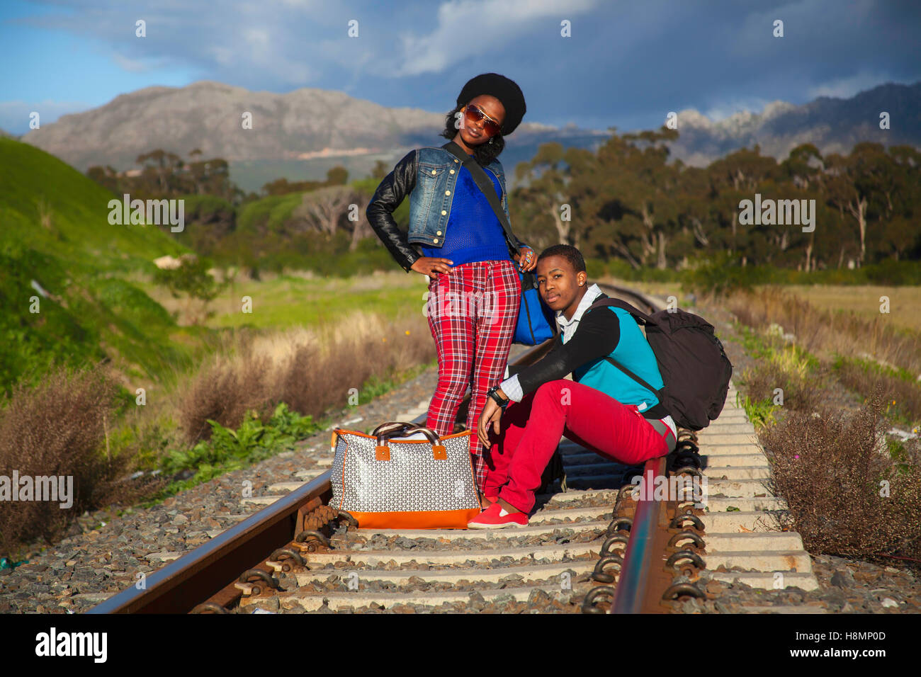 afrikanischer Mann und ein Mädchen warten auf Zug auf den Gleisen Stockfoto