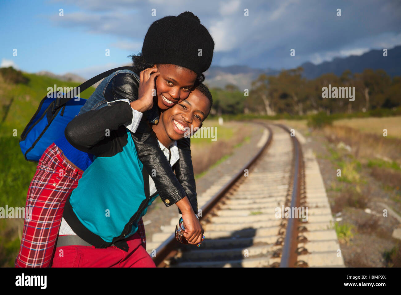 afrikanischer Mann und ein Mädchen warten auf Zug auf den Gleisen Stockfoto