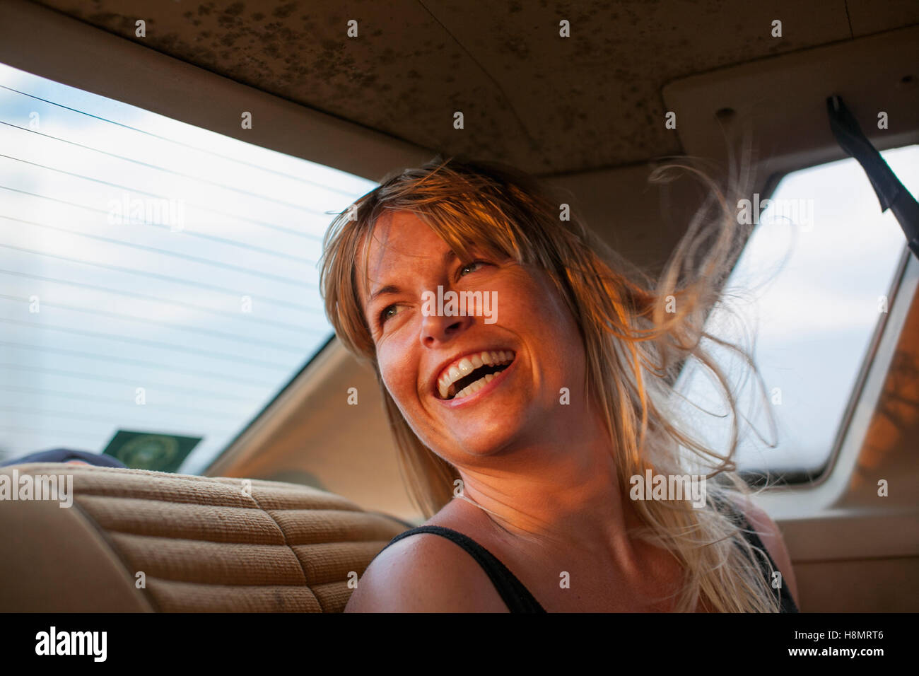 Blonde Frau lachend auf dem Rücksitz des Wagens Stockfoto