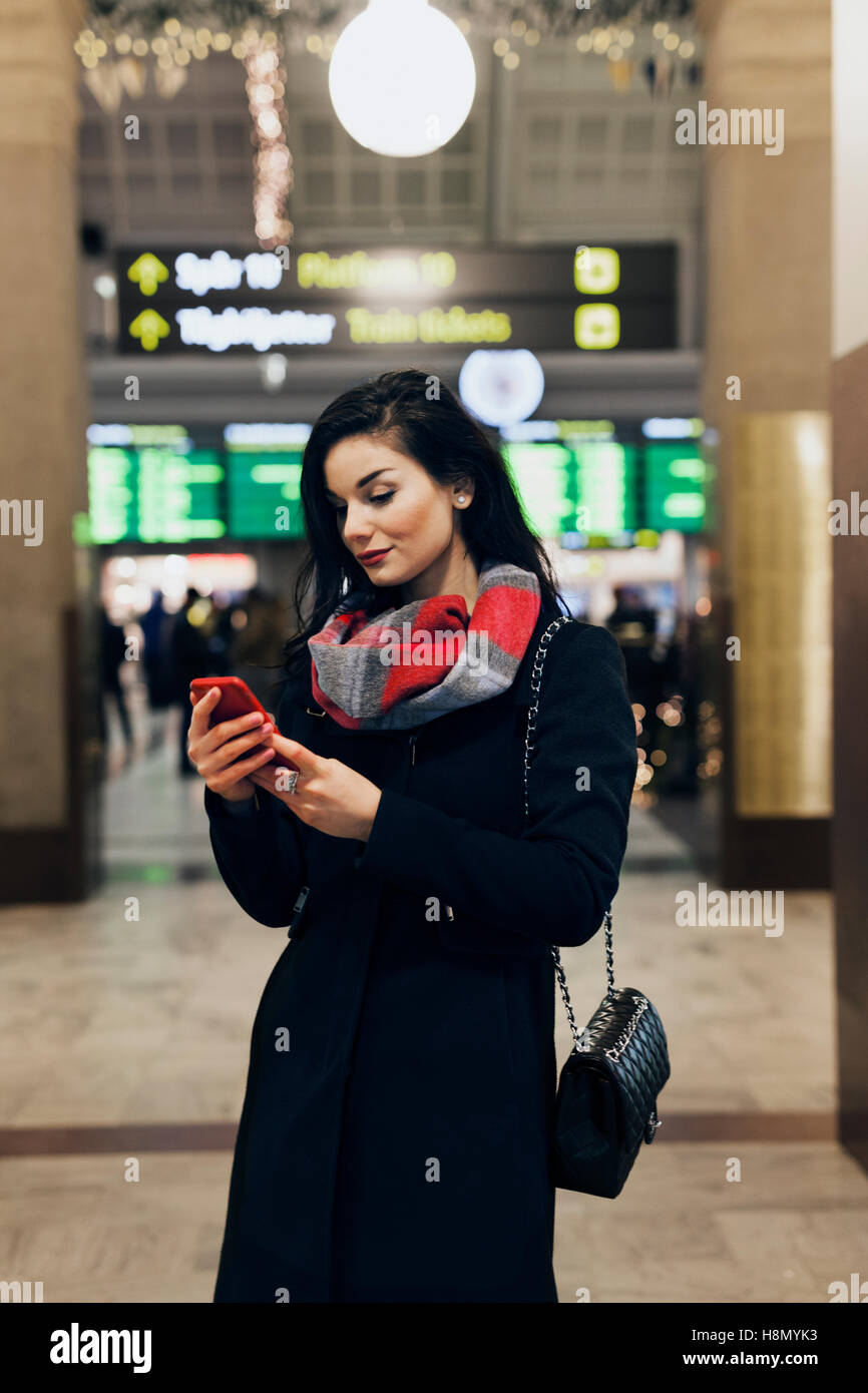 Junge Frau mit Smartphone am Bahnhof Stockfoto
