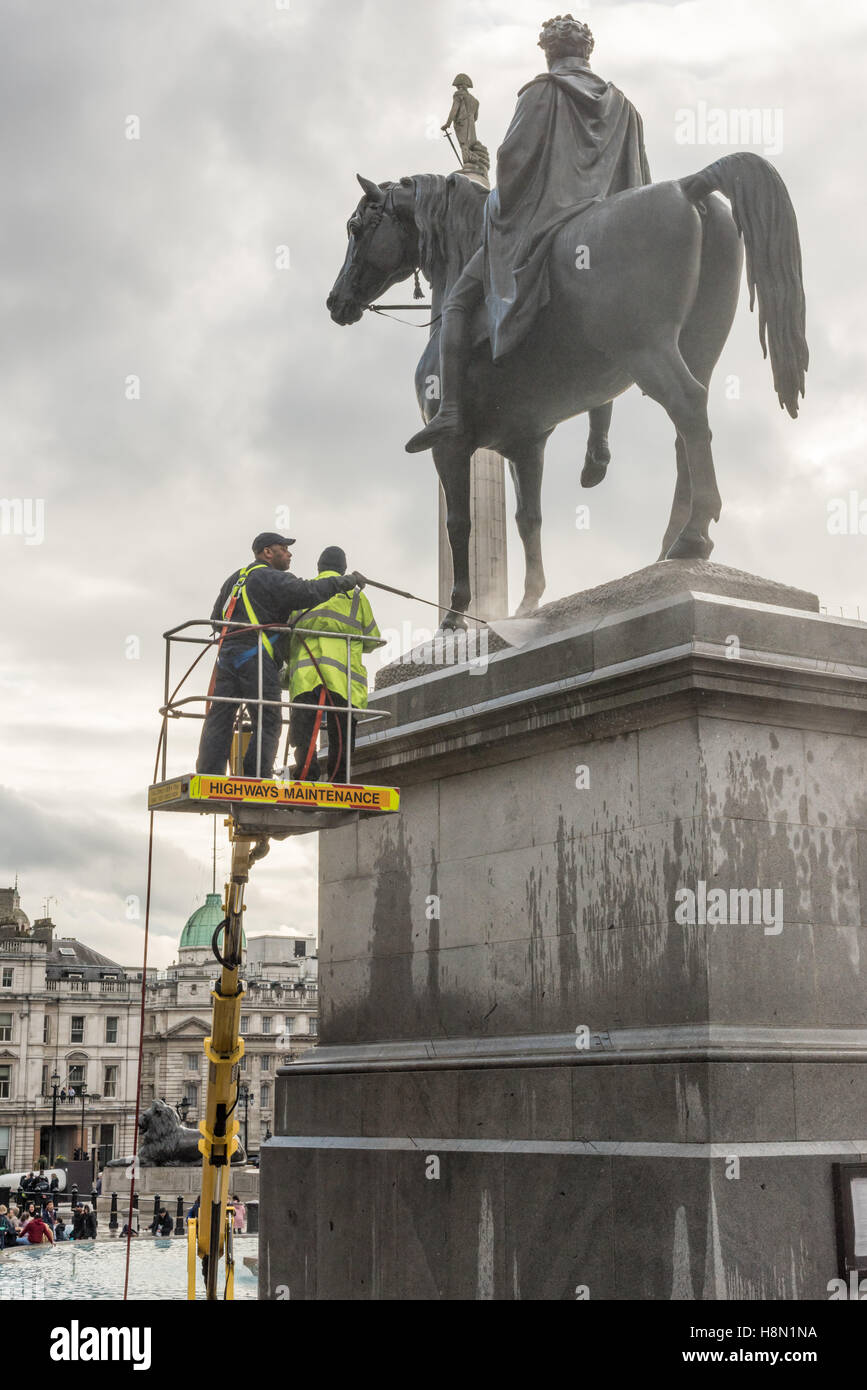 Arbeiter auf einem cherrypicker sprühen Wasser auf eine bronzene Statue von König George IV und sein Pferd auf dem Trafalgar Square, London, UK. Stockfoto