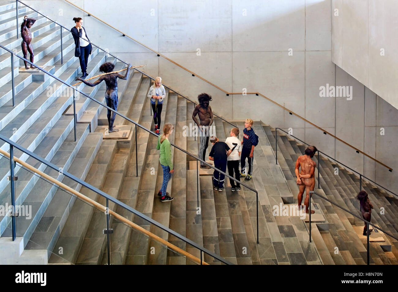 Breite Treppe mit Steinzeitmensch Repliken und Besucher. Moesgaard Museum, Aarhus, Dänemark. Architekt: Henning Larsen, 2015. Stockfoto