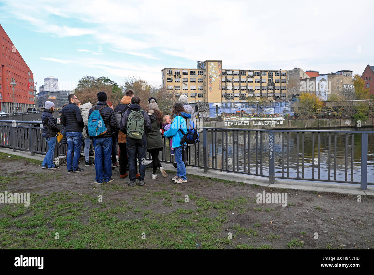 Tour Gruppe Touristen versammeln sich gegenüber "Flüchtlinge willkommen" unterzeichnen auf der Ufermauer an der Spree in Friedrichshain, Berlin Herbst 2016 KATHY DEWITT Stockfoto