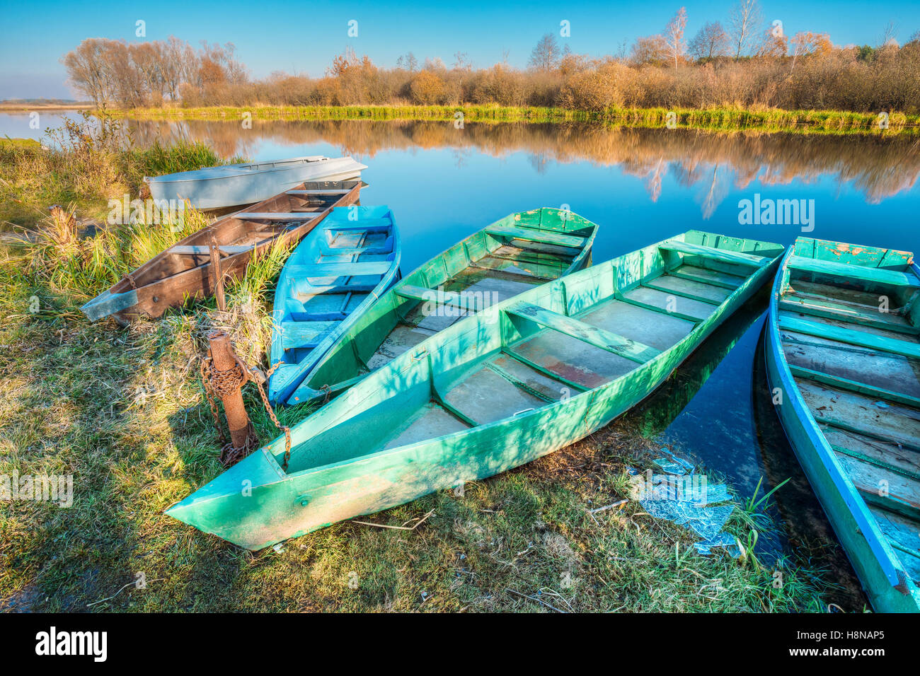 Der Herbst Ufer festgemachten alten hölzernen Angeln Ruderboote Skippets Herbst hinterlassen bewegungslos Flusswasser mit Ic flott Stockfoto