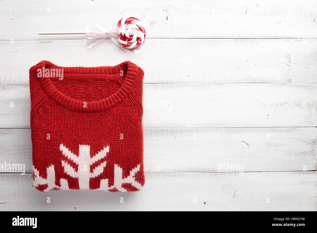 Winter Urlaub gestrickte Pullover und Weihnachten Lutscher auf weißem Hintergrund aus Holz. Stockfoto