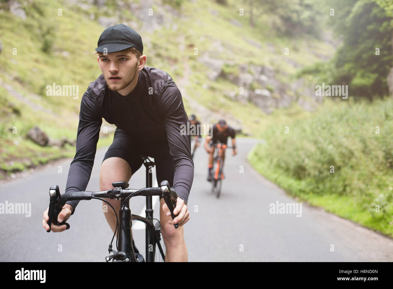 Ein junger Radfahrer steht an der Spitze, während ein lustiges Rennen mit Freunden Stockfoto