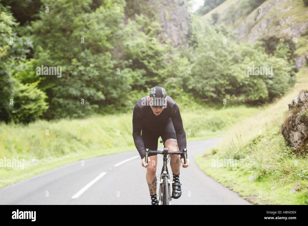 Eine tätowierte Hipster Radfahrer Klettern einen Hügel in Cheddar George Stockfoto