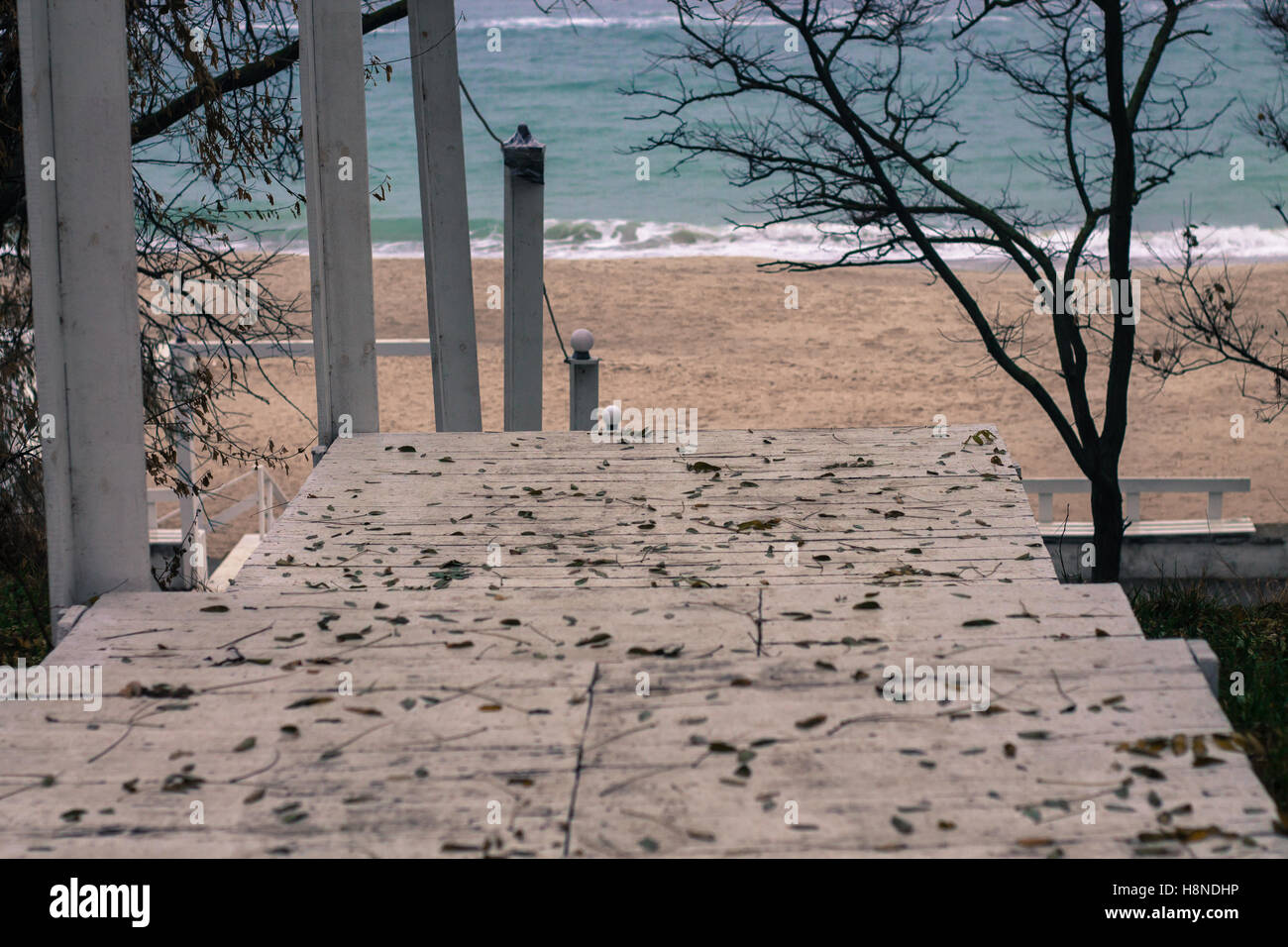Weiße Holztreppen Strand. Abstieg. Blaue Mineralwasser. Küste des Schwarzen Meeres, Odessa, Ukraine. Gefallene Herbstlaub Stockfoto