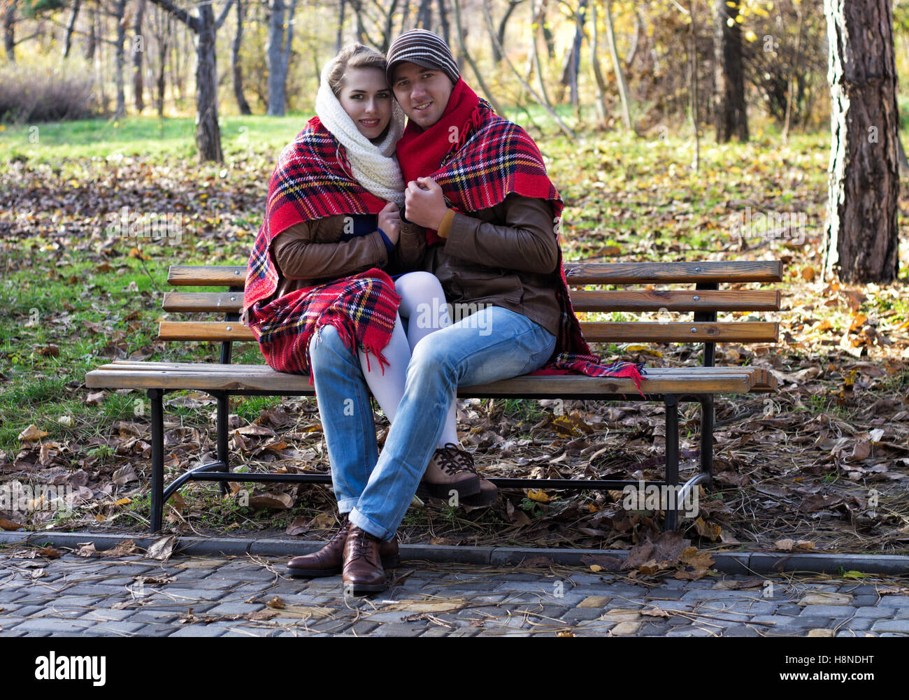 Junges Paar auf Bank im Park sitzen in Plaid/Decke bedeckt. Herbstsaison. Stockfoto