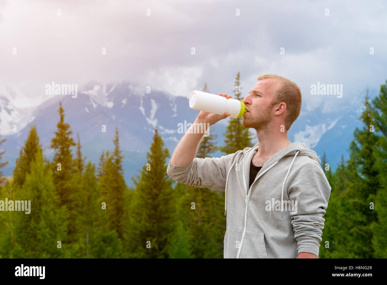 Männer Läufer Trinkwasser im Freien. Hintergrund der Berge. Stockfoto