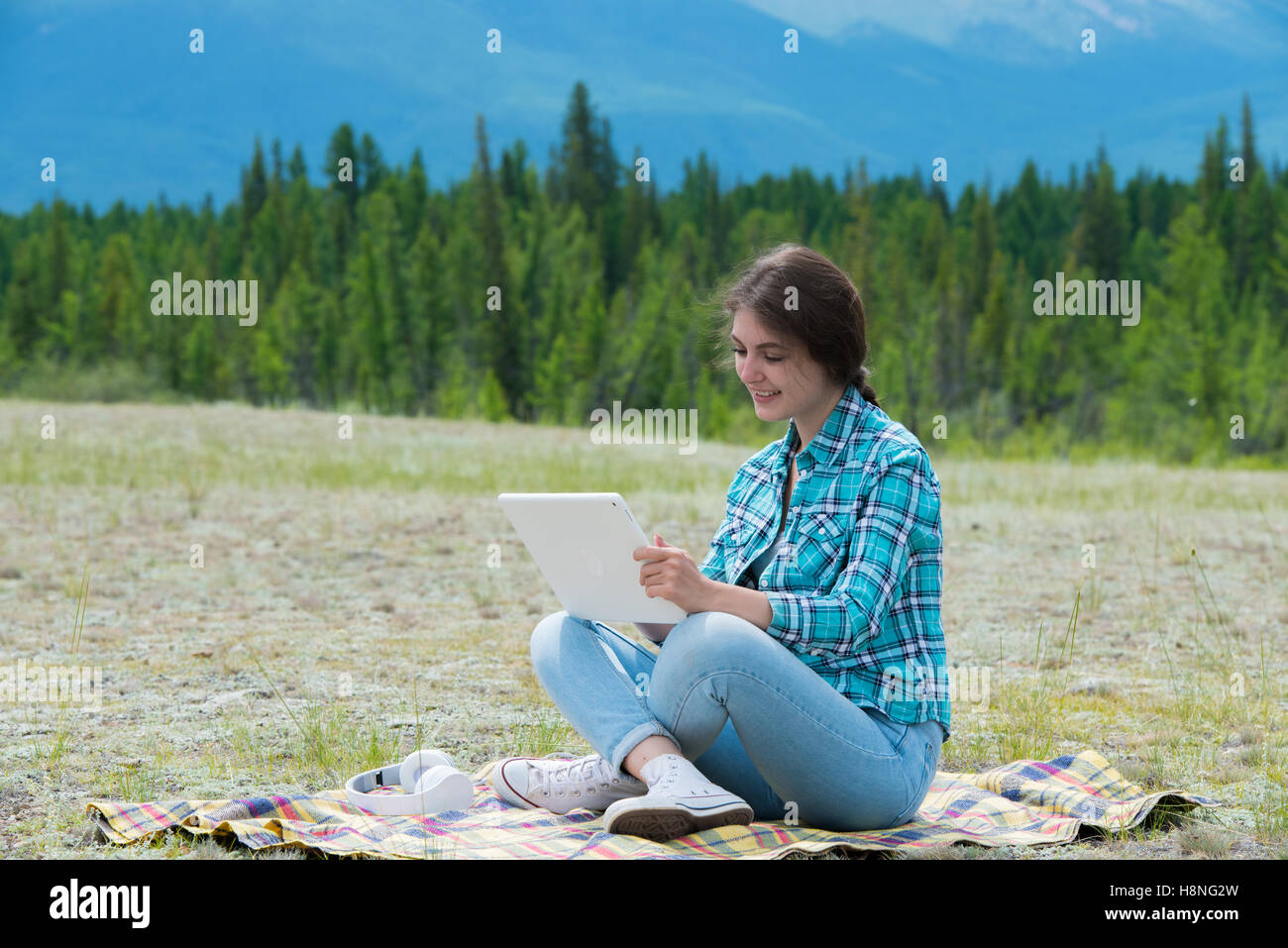 Schöne Mädchen in einem Feld auf Berge, TabletPC verwenden. Stockfoto