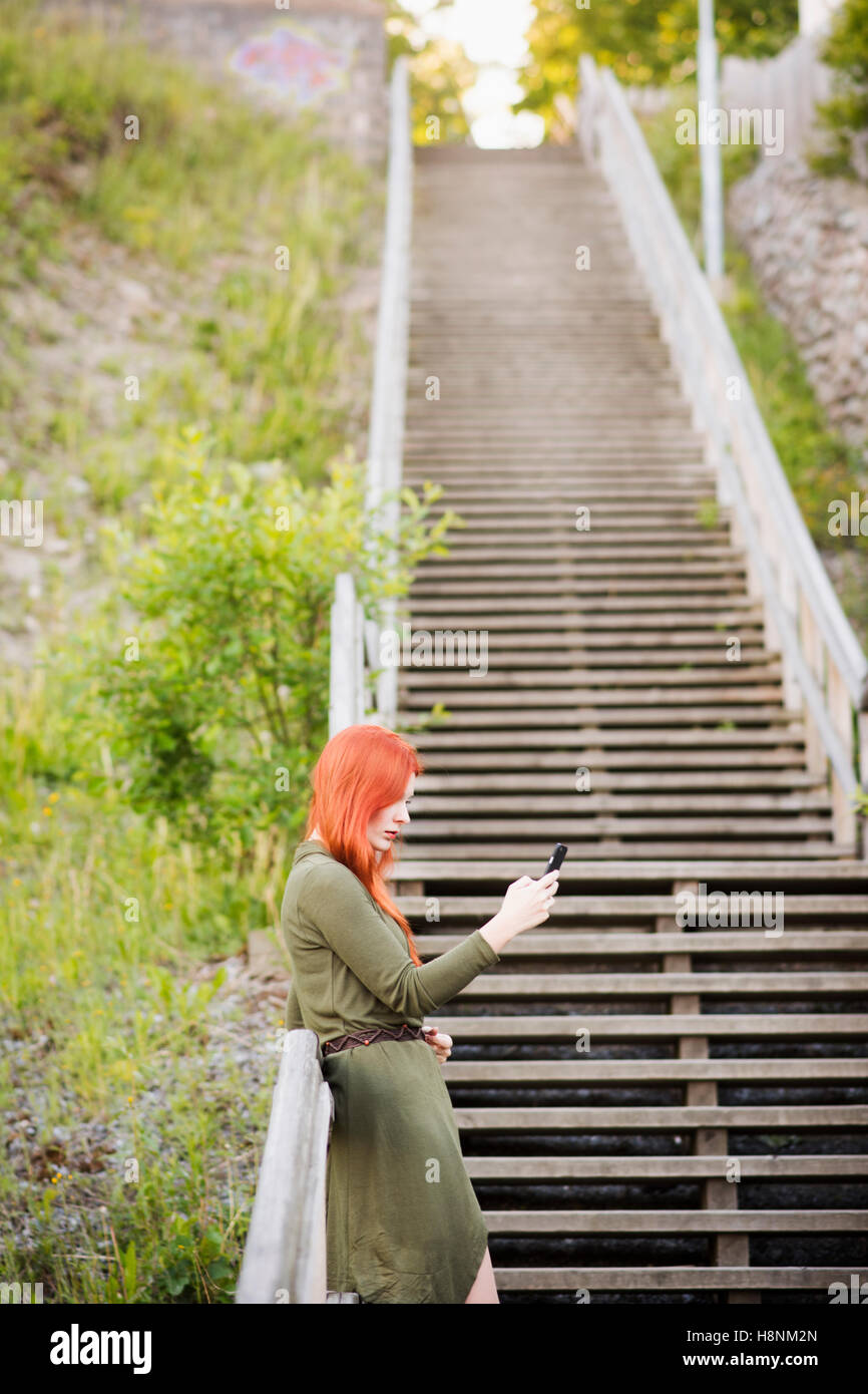 Rothaarige Frau auf der Treppe stehen und mit Telefon Stockfoto