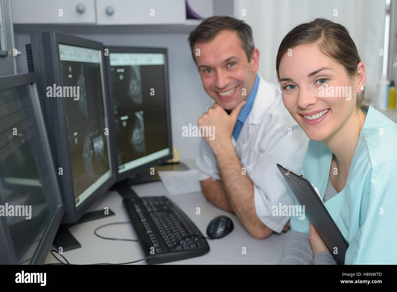 Porträt von zwei Ärzten, die lächelnd im Überwachungsraum im Krankenhaus Stockfoto