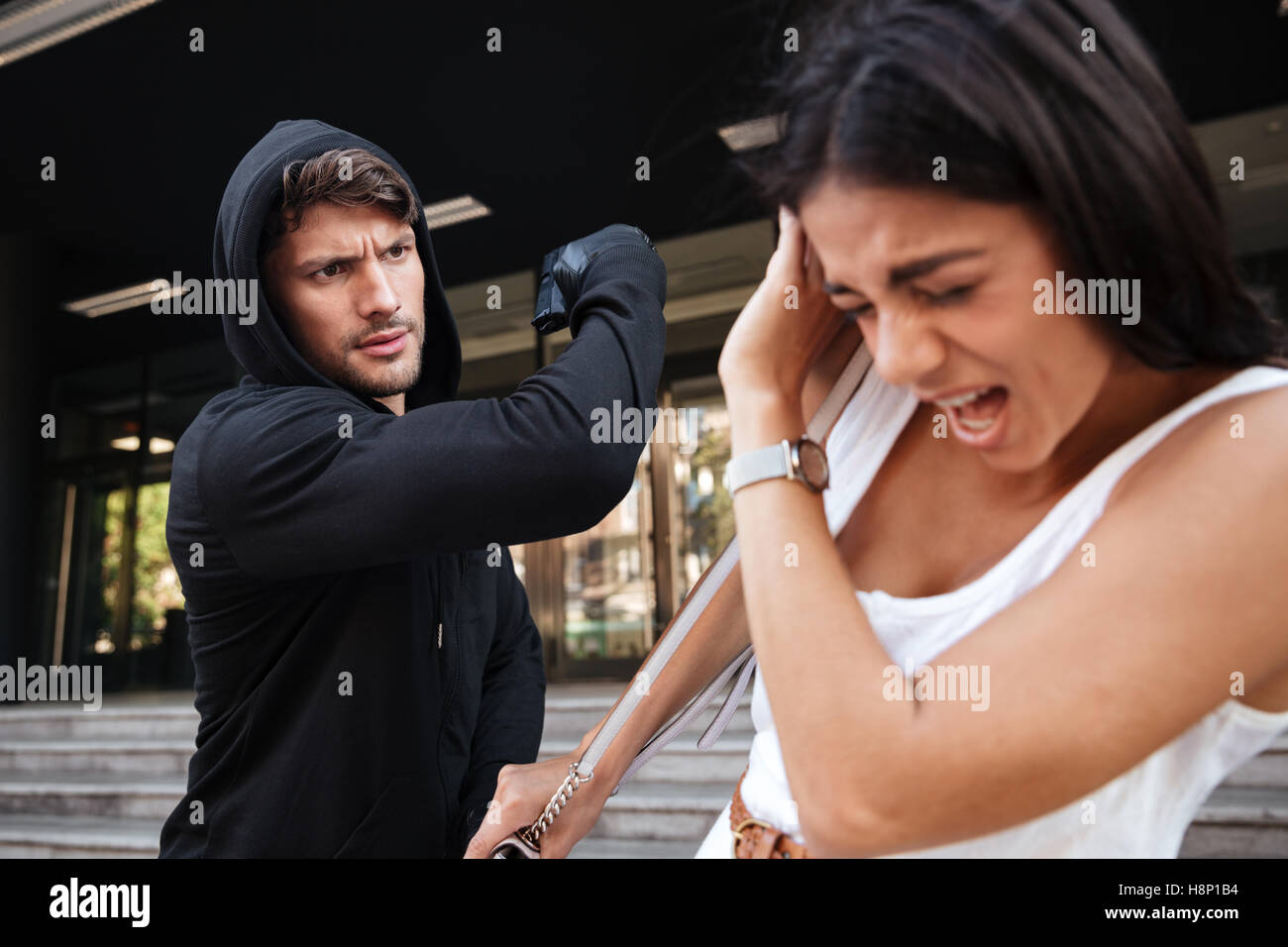 Dieb Mann mit Gewehr Angriff Angst junge Frau auf der Straße Stockfoto