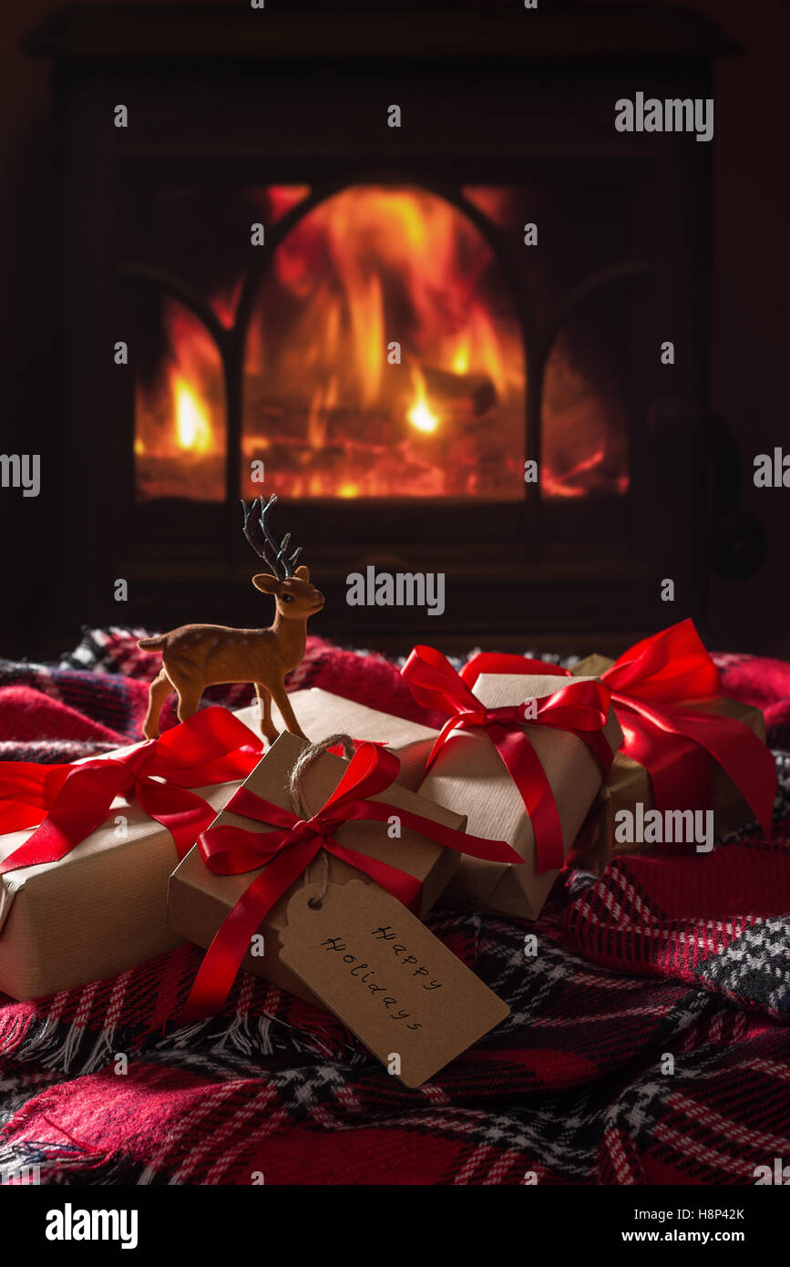 Verpackte Weihnachtsgeschenke von einem gemütlichen Feuer entzündet Stockfoto