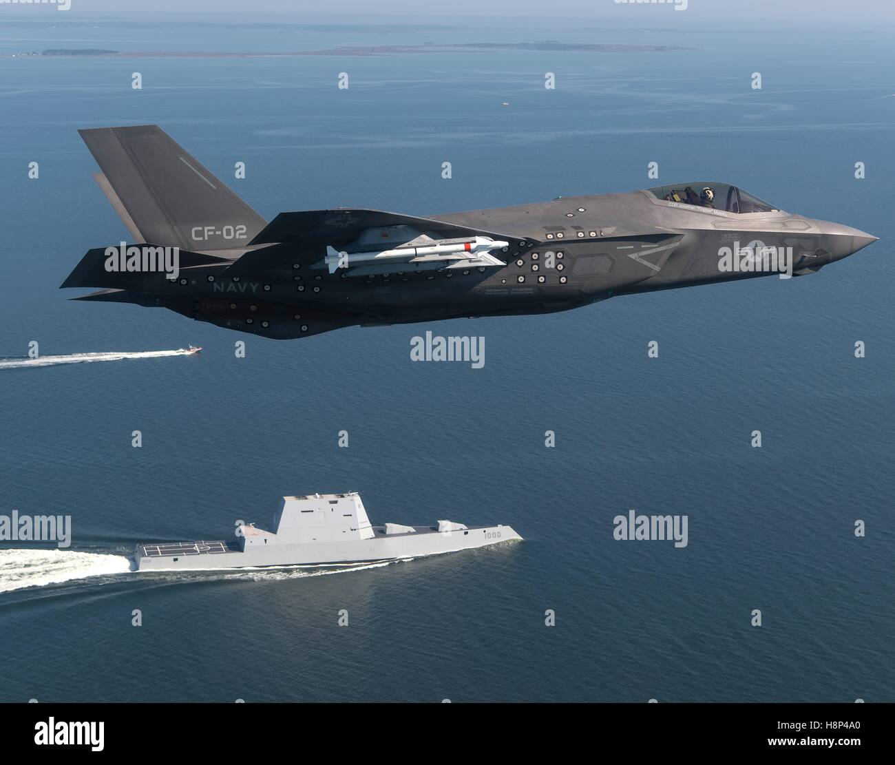 Ein f-35 Lightning II Tarnkappenjäger multirole Flugzeug fliegt über die USN Zumwalt-Klasse geführte Flugkörper Zerstörer USS Zumwalt als Schiff Transite der Chesapeake Bay 17. Oktober 2016 in Patuxent River, Maryland. Stockfoto