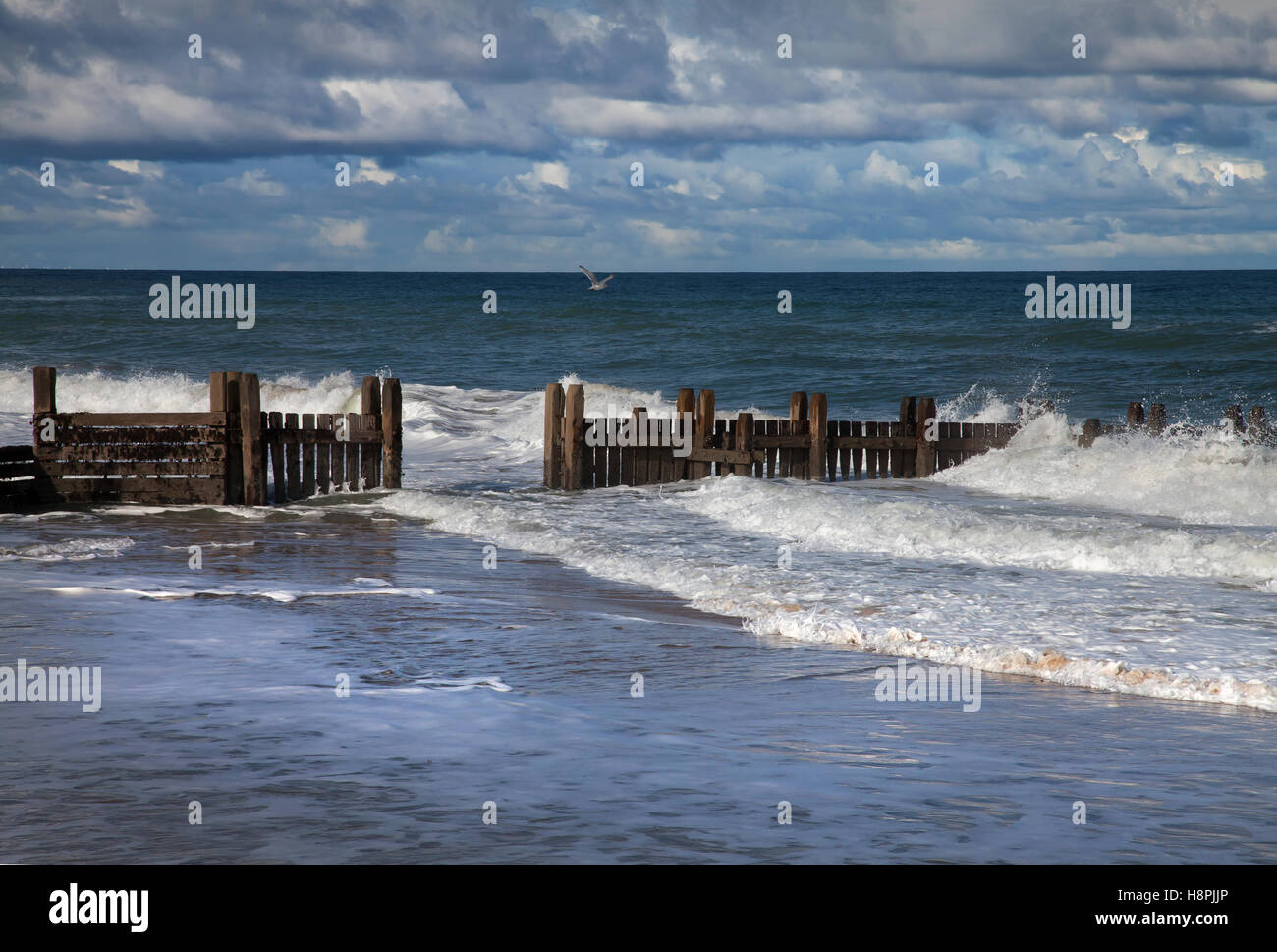 Wellen brechen über die Stützmauer Küstenschutzes an der North Norfolk-Küste Stockfoto