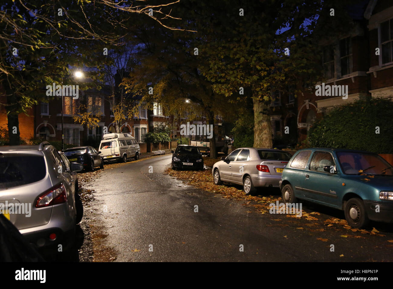 Herbst Blätter bedecken die Bürgersteige und Straßen in einer typischen Süd-London-Straße nach Einbruch der Dunkelheit auf eine nasse Nacht Stockfoto