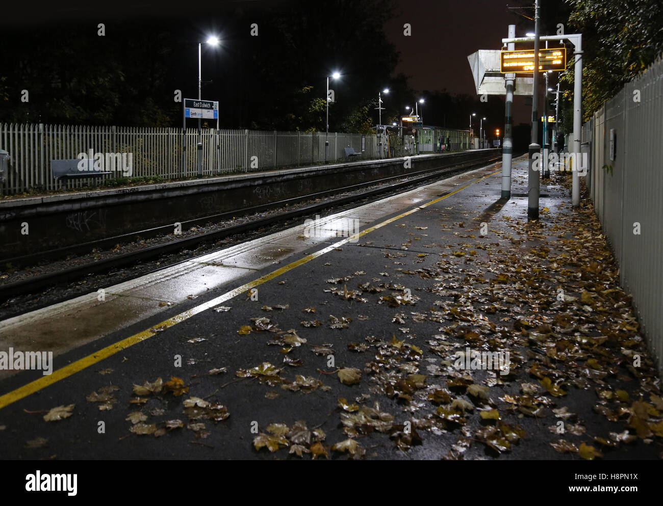 Herbstblätter auf der Strecke und die Plattform auf ein South London Railway Station. Blätter sind berüchtigt für die Entstehung von Zugverspätungen. Stockfoto