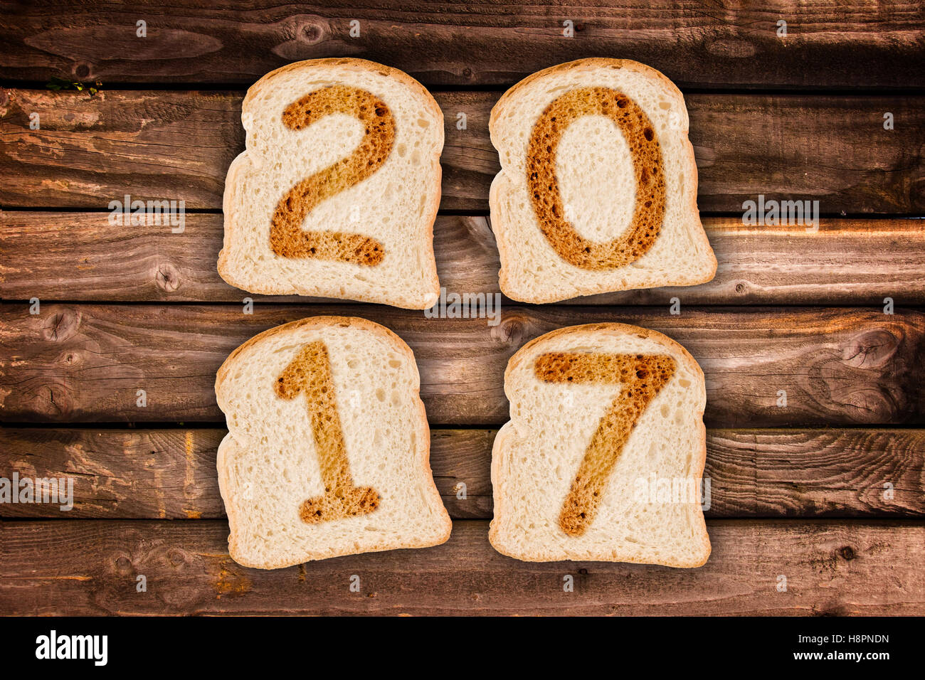 2017-Grußkarte geröstete Brotscheiben auf Holzbohlen Hintergrund Stockfoto