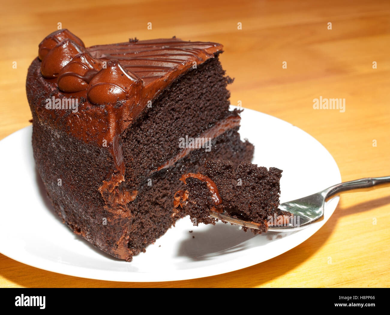 Schokoladen-Kuchen mit Schokolade Zuckerguss auf einem weißen Teller Stockfoto