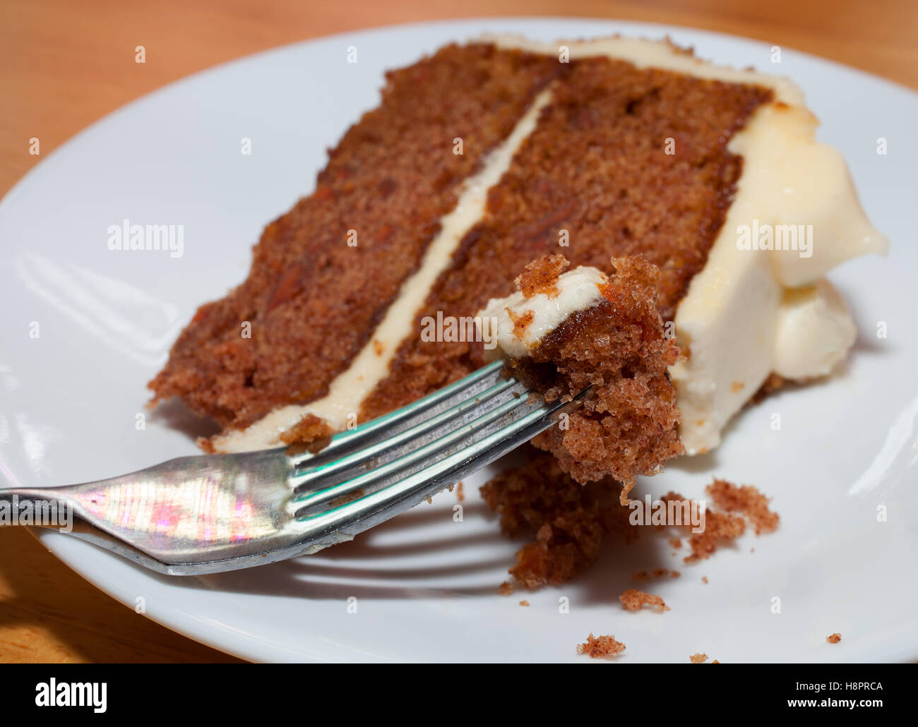 Karotte-Kuchen-Stück auf einer Gabel mit einer Scheibe hinter Stockfoto