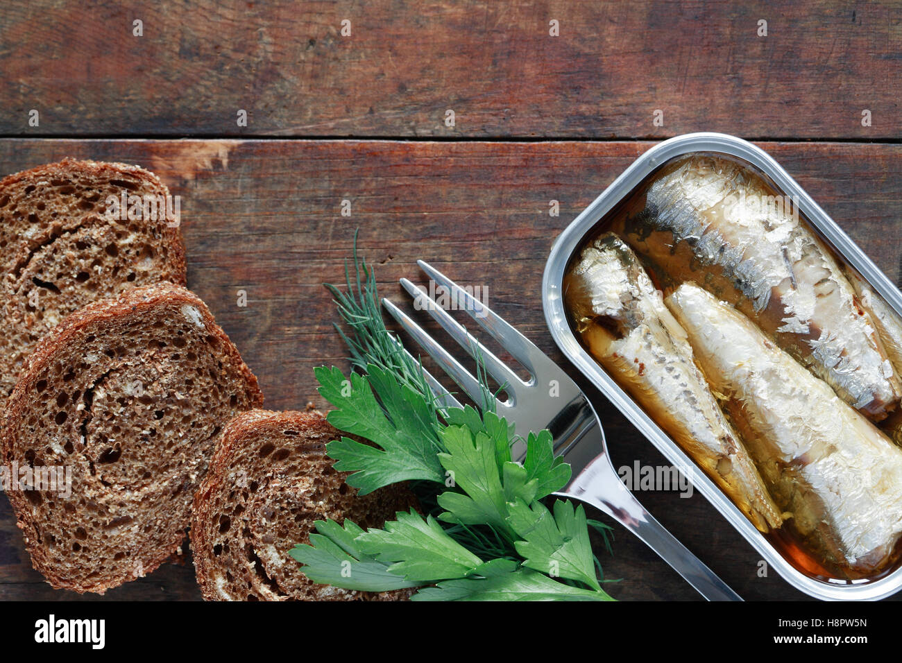 Fischkonserven in der Nähe von geschnittenem Brot auf hölzernen Hintergrund Stockfoto