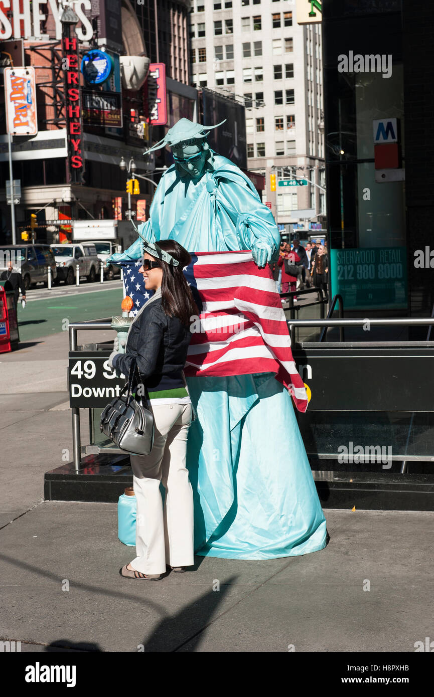Times Square, Straßenkünstlerin, Straßenmusiker, verkleidet als Freiheitsstatue, posiert für ein Foto mit einer weiblichen Touristen. Stockfoto