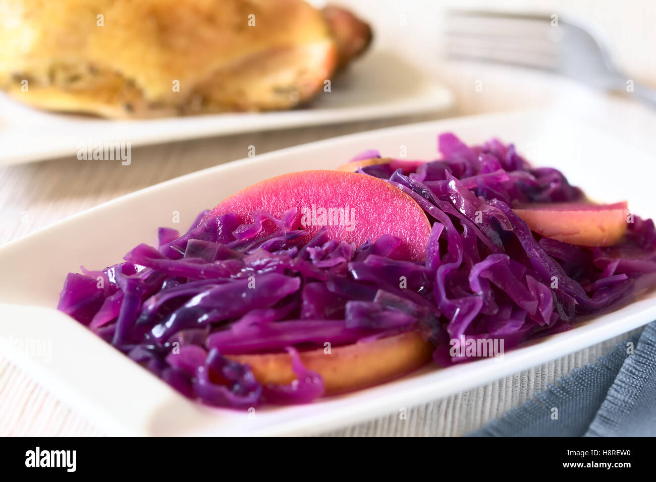 Geschmorter Rotkohl mit Apfel auf Platte, mit Gebratene Hühnerkeule im ...