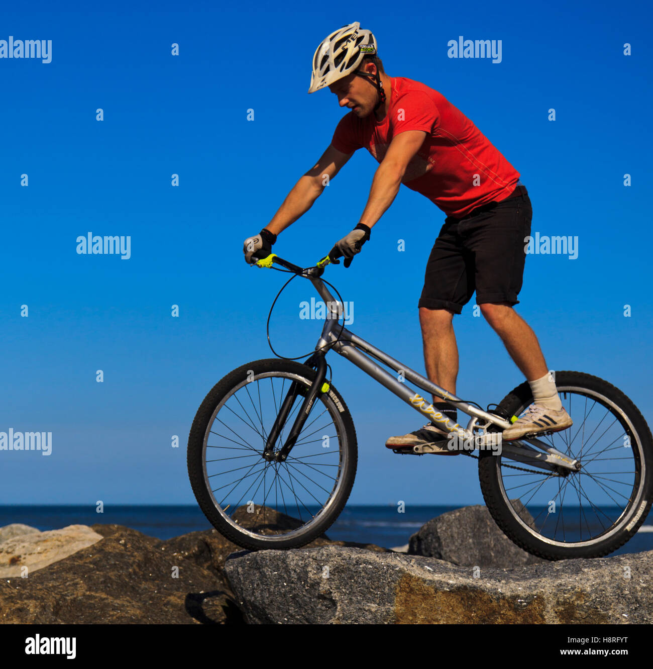Mountainbiker, springen über Felsen auf der Hafenmauer in Staithes, North Yorkshire Stockfoto