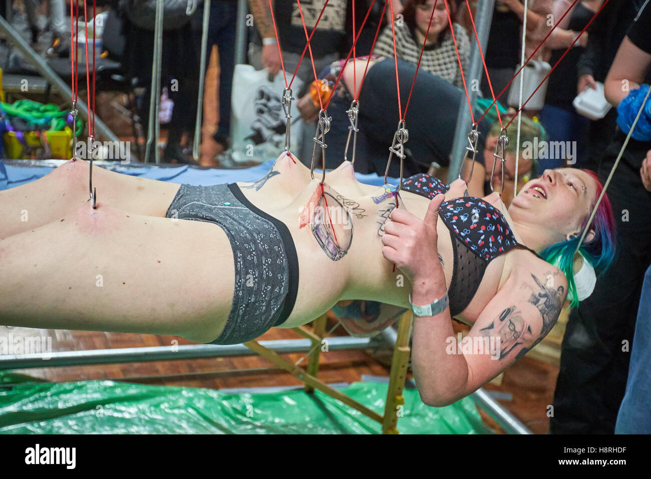 Eine Frau wird von 10 Körper Haken durch Mitglieder des Zustand der Glückseligkeit aufgehängt. Stockfoto