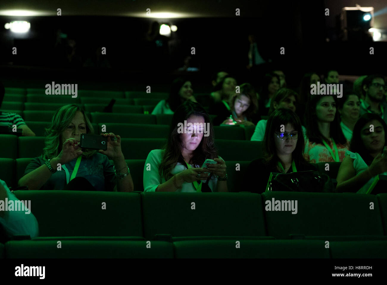 Junge Frau überprüft ihr Telefon im Kino Stockfoto