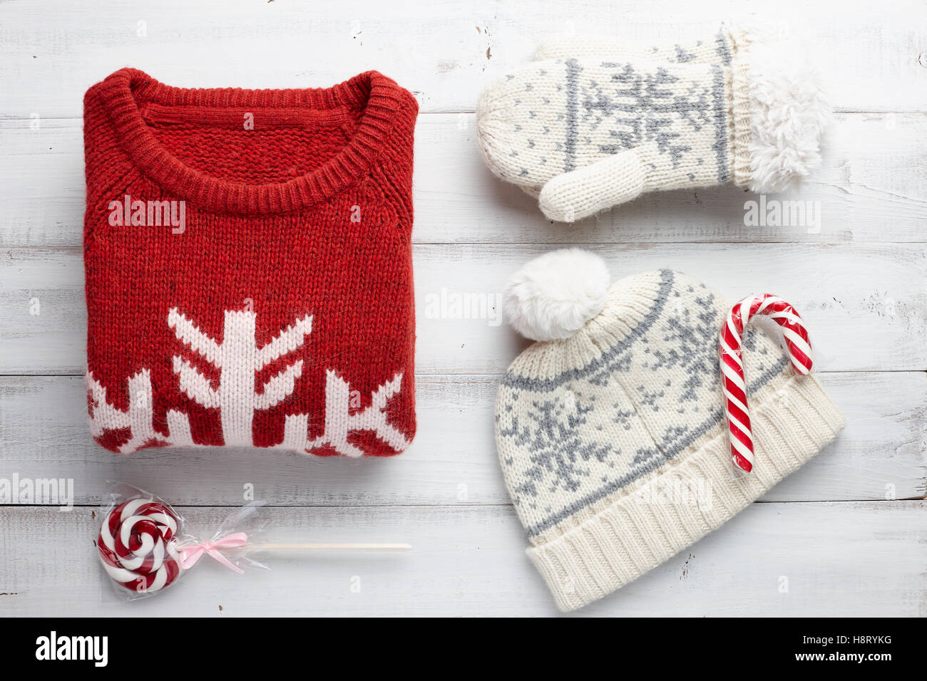 Winterurlaub, gestrickte Pullover, Handschuhe, Mütze und Weihnachten Lutscher auf weißem Holz Hintergrund Stockfoto
