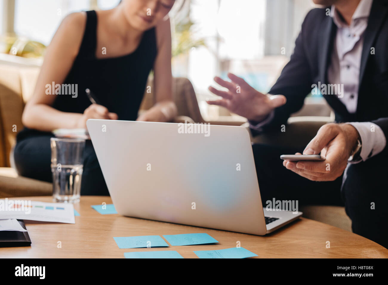 Schuss von Geschäftspartnern zusammenarbeiten auf Laptop im Büro. Mann, Mobiltelefon und Frau Notizen schreiben. Stockfoto