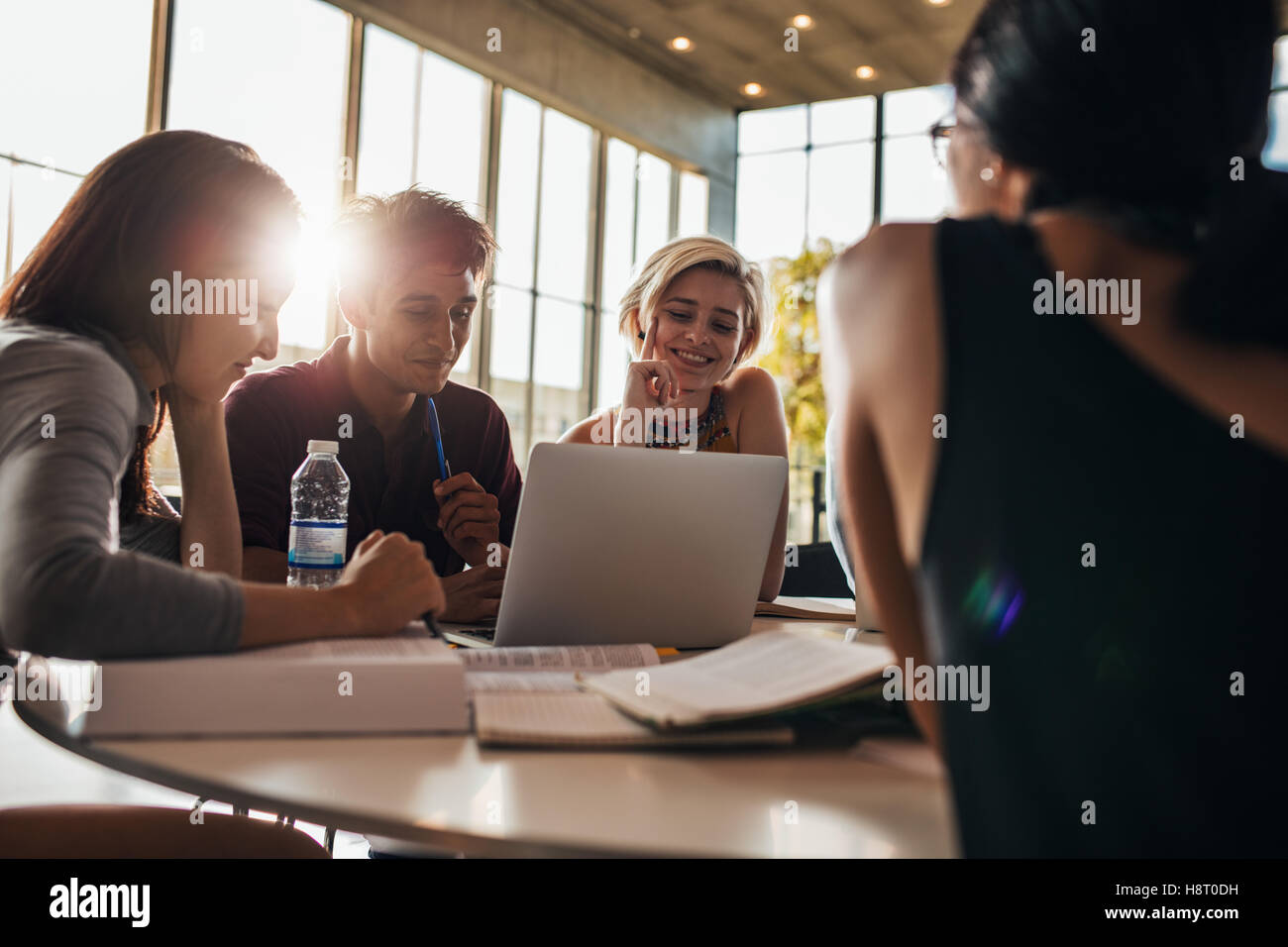 Mann und Frau, die im Unterricht zusammen sitzen. universitätsstudenten, die in der Bibliothek an einem Laptop arbeiten. Stockfoto