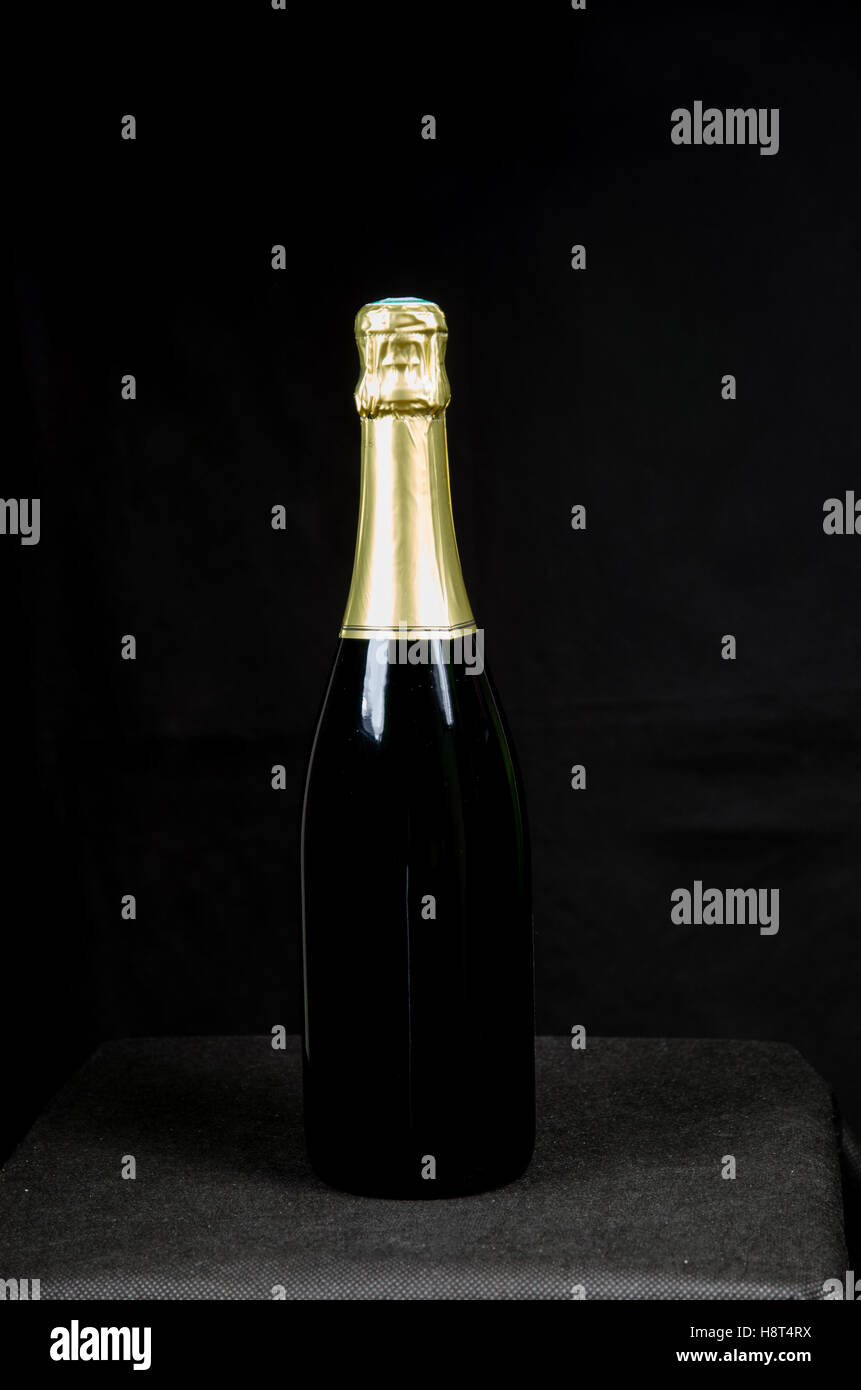 Eine versiegelte Flasche Sekt an einem schwarzen Hintergrund Stockfoto