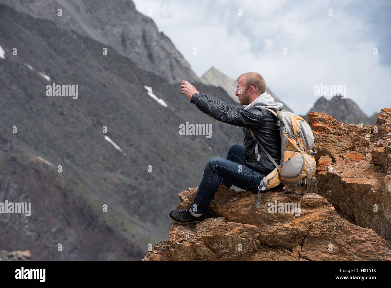 Tourist mit einem Rucksack sitting on Top of Mountain und fotografieren das Telefon. Die Höhe von 3000 Meter. Stockfoto