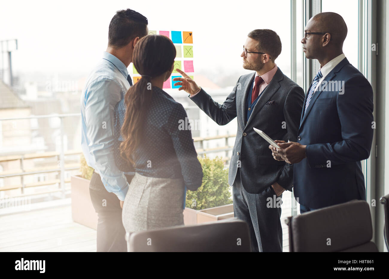 Gemischtrassig Business Team stehen Brainstorming zusammen vor einem hellen Großansicht Fenster im Büro auf einen Satz Stockfoto