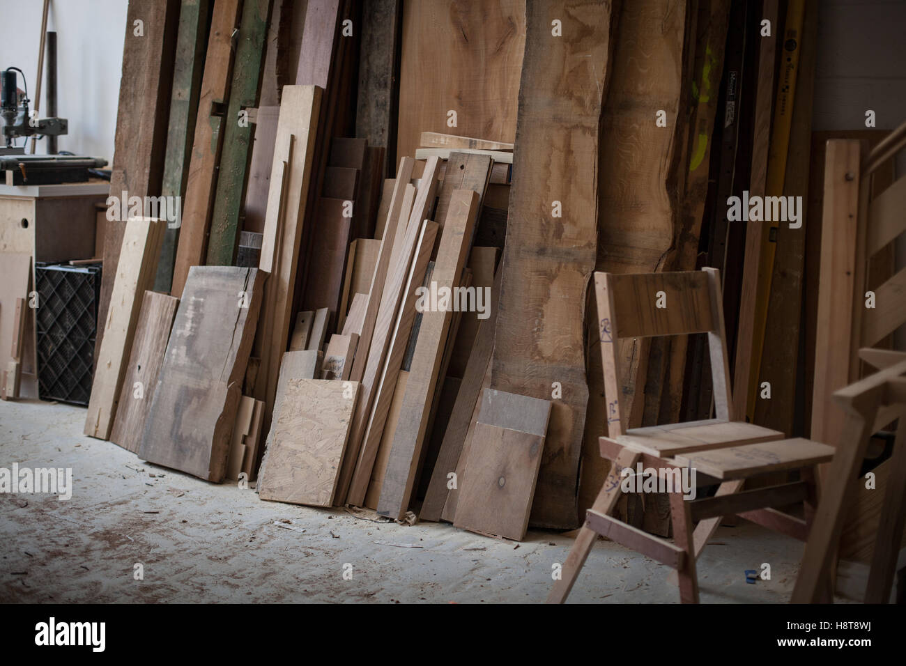 Detail einer Möbelwerkstatt Entscheidungsträger zeigt Holz gestapelt und eine unvollendete Stuhl Stockfoto