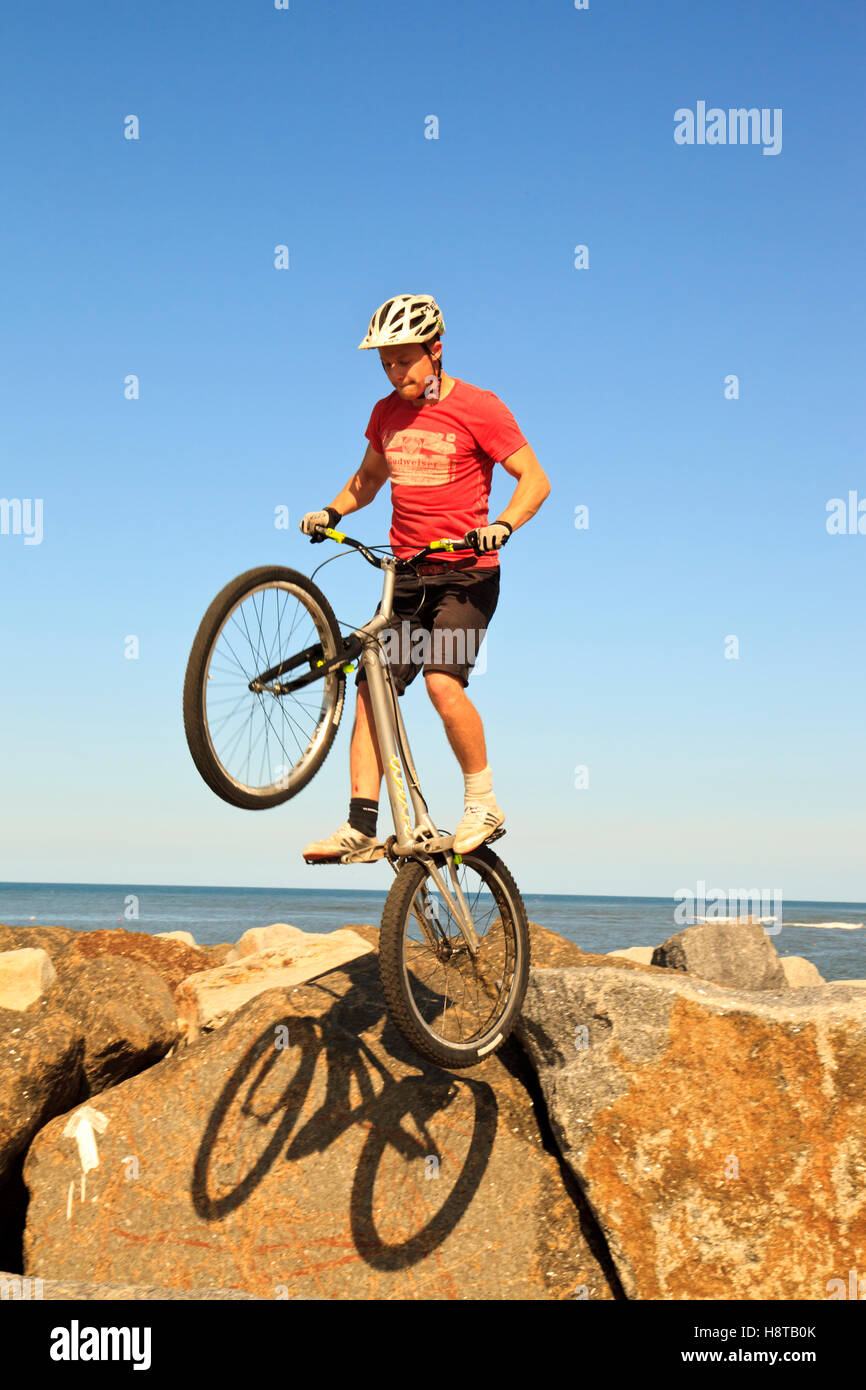Mountainbiker, springen über Felsen auf der Hafenmauer in Staithes, North Yorkshire Stockfoto